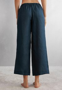 Navyblaue Leinen-Hose mit weitem Bein und elastischem Bund, ausgestattet mit einer glatten Oberfläche und sauberen Säumen. Entworfen für eine lockere Passform.