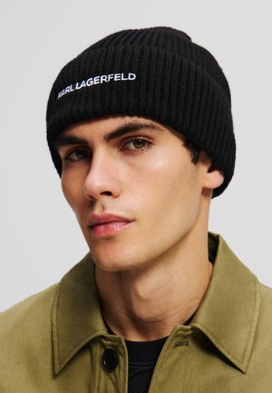 Schwarze, gerippte Strickmütze mit dem weißen Schriftzug "KARL LAGERFELD" bestickt. Trägt zu einer khakifarbenen Jacke und zeigt einen lässigen Stil.