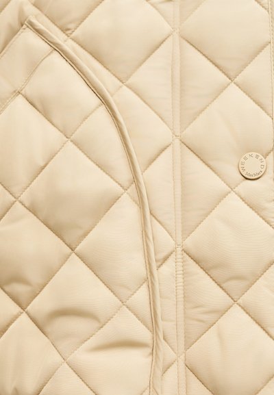 Μπεζ υφασμάτινη επένδυση με ραφή σε σχέδιο διαμαντιού, καμπυλωτή ραφή και ένα μικρό στρογγυλό κουμπί με την ένδειξη "WEEKEND Max Mara".