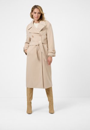 Beige long coat with a double-breasted design, wide lapels, tied waist belt, buttons on sleeves, and side pockets.