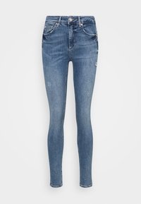 Vaqueros ajustados en denim azul claro con un acabado desgastado. Presentan un ligero desgaste, diseño de cinco bolsillos y cierre frontal con botón.