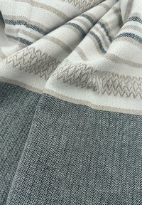 Geweven stof met een structuurpatroon in beige, wit en zwarte strepen. Zachte, multitonale textuur verhoogt de visuele interesse.