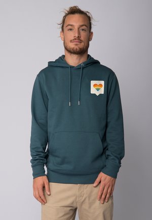 Kapuzensweatshirt aus türkisfarbenem Stoff mit einer Kängurutasche. Verfügt über ein quadratisches Patch mit einem Regenbogenherz-Graphic. Schnürung am Hals.