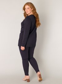 Marineblauw lange mouw top met een relaxte pasvorm, gecombineerd met bijpassende strakke leggings. Bevat een gladde textuur en eenvoudige, strakke lijnen.