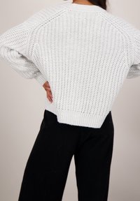 Jersey de punto gris claro con un ajuste holgado, puños y bajo acanalados, que presenta un diseño texturizado y mangas raglán.