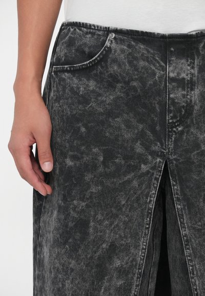 Mustahreen mustahreen jaa gillini denim skirt ka with a faded, distressed texture, jo ek side slit aur front pocket ke saath hai. Stitching ka rang contrasting hai.