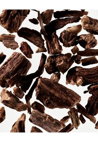 Morces de copeaux de bois bruns et beige de formes et tailles variées, présentant une texture rugueuse et des motifs de grains naturels sur un fond blanc.