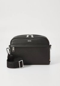 Svart messenger-väska av texturerat material, med silverfärgade detaljer, dragkedja upptill och avtagbar justerbar rem.