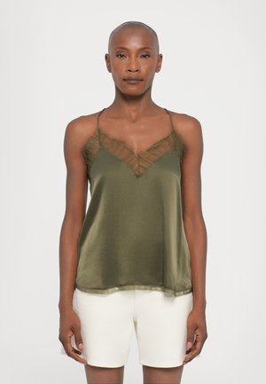 Camiseta de satén verde oliva con detalles texturizados transparentes en el escote y tirantes ajustables, combinada con shorts de color crema.