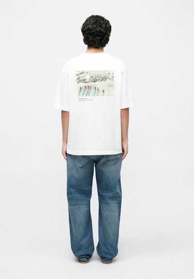 White cotton t-shirt with a rectangular graphic on the back featuring a snowy landscape and figures skiing. Relaxed fit with short sleeves.