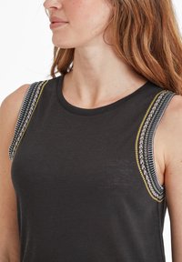 Black sleeveless top with round neckline. Features contrast embroidered detailing in yellow, green, and white along the shoulder seams.