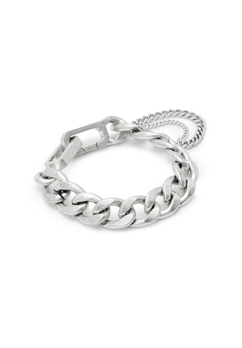 Bracelet en métal argenté avec des maillons entrelacés et un fermoir plat et rectangulaire, agrémenté d'une chaîne fine supplémentaire.