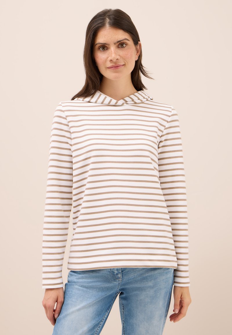 Camiseta de manga larga a rayas en blanco y marrón claro, con capucha y tejido suave de corte relajado. Combinada con jeans de mezclilla azul claro.