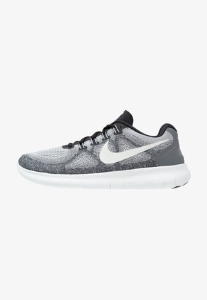 Grijze en zwarte sport schoenen met een gemêleerde gebreide bovenkant, witte zool en een opvallende witte Nike swoosh aan de zijkant.
