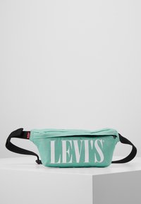 Marsupio teal chiaro realizzato in tessuto resistente. Presenta un audace logo bianco "LEVI'S", una cintura nera regolabile e una chiusura con zip.