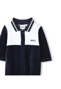 Combinaison de style polo bleu marine en tissu doux, avec un panneau supérieur blanc, des manches courtes et une fermeture à boutons ornée du logo « BOSS ». 