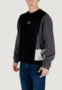 Felpa nera e grigia a collo rotondo con un design a blocchi di colore e un accento bianco. Presenta un logo sul petto, realizzata in tessuto morbido.