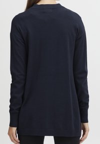 Marinblå långärmad tröja med rund halsringning, ribbade manschetter och sidoflikar för ökad komfort. Slät textur, minimalistisk design.