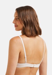 Soutien-gorge rose clair avec une finition lisse, des bretelles réglables et une fermeture à crochets. Design simple avec un minimum d'ornements.