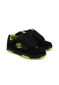 Zapatillas de skate negras y verdes con parte superior de gamuza, suela de goma, lengüeta acolchada y cordones gruesos negros. Presentan un logo verde en el lateral.