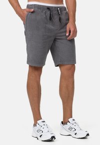 Grå corduroy shorts med elastrisk talje, sidelommer og lige snit, parret med hvide atletiske sneakers.