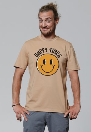 Beige katoenen t-shirt met een grote gele smiley face graphic met de tekst "HAPPY TIMES" erboven in zwarte letters. Korte mouwen, ronde hals.