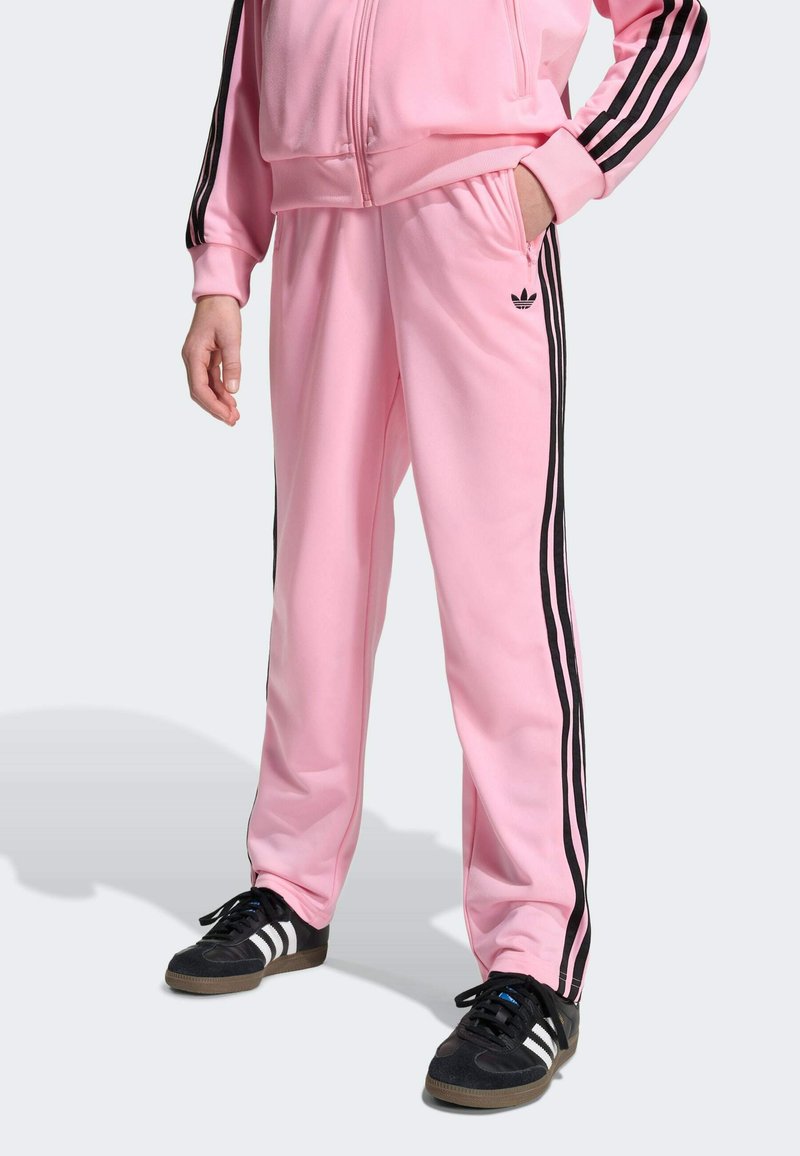 Rosa Trainingshose aus glattem Stoff mit schwarzen Seitenstreifen und kleinem Logo. Die Hose hat einen elastischen Bund und Seitentaschen.