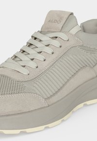 Baskets en daim et maille gris clair avec lacets blancs, semelle en caoutchouc épaisse, et nom de marque "ALDO" sur la languette.