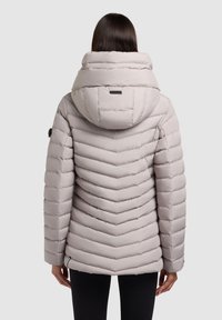 Polstret jakke i lys grå med en chevron-mønster, høj krave og aftagelig hætte. Inkluderer sidelommer og elastiske manchetter.
