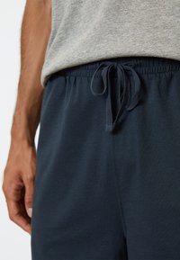 Marineblaue Sweatpants mit elastischem Bund und Kordelzug. Der Stoff wirkt weich mit glatter Struktur und einem lässigen Schnitt.