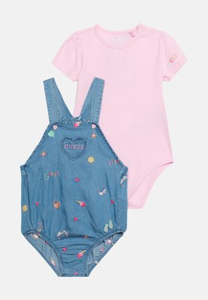 Body bébé rose à manches courtes avec "GUESS" sur la manche et grenouillère sans manches en denim avec broderie colorée sur le thème de l'été et écusson logo cœur.