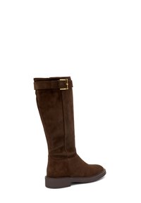 Bota alta de ante marrón, con punta cuadrada, suela plana y una correa decorativa con una hebilla dorada cerca de la parte superior. Textura suave.