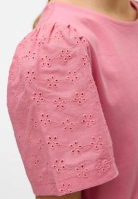 Różowa koszulka z bufiastymi rękawami, zdobiona haftem kwiatowym i detalami ażurowymi, wykonana z miękkiego materiału bawełnianego. Dopasowany krój.