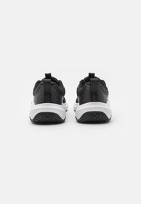 Zwarte sportieve schoenen met een gemetste mesh bovenkant, witte tussenzool en zwarte rubberen buitenzool met een logo. Twee trekkoorden op de hiel voor gemakkelijk aan- en uittrekken.