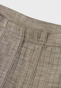 Tissu côtelé beige avec une taille élastique visible et des détails de couture, mettant en valeur un motif de surface texturé pour une dimension ajoutée.