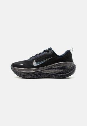 Chaussure de course noire Nike avec swoosh argenté, semelle amortie et design avec lacets, présentée de profil sur fond uni.