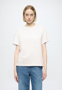 Tricou din bumbac bej deschis, cu mâneci scurte și gât rotund. Are un logo mic albastru pe partea stângă a pieptului. Asortat cu pantaloni scurți din denim albastru.