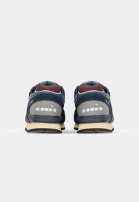 Navy and maroon sports shoes with grey accents, featuring the "diadora" logo, viewed from the back on a white background.