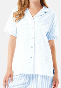 Camisa de pijama azul claro en tejido texturizado, con un cierre de botones en la parte delantera, mangas cortas y un bolsillo en el pecho con detalles a rayas en el cuello y las mangas.