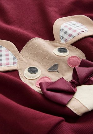 Burgundowa bluza z aplikacją beżowej twarzy zwierzęcia z kratkowymi uszami, haftowanymi detalami i akcentem w postaci ciemnofioletowej kokardy.
