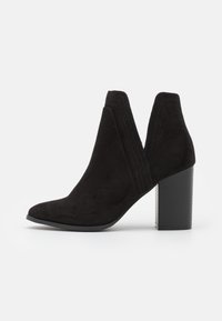 Svarta mocka ankelskor med spetsig tå, elastiska sidopaneler och en texturerad klack, med tonande sömnadsdetaljer.