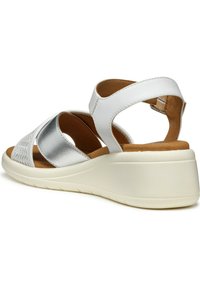 Sandalo bianco con dettagli argento, caratterizzato da un design perforato, una cintura regolabile e una suola a zeppa imbottita per il comfort.