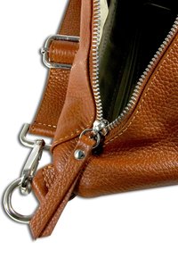 Bruine leren handtas met een gestructureerde afwerking, zilveren ritssluiting en metalen beslag. Verstelbare riem en zichtbare voering aan de binnenkant.