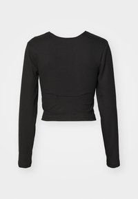 Must have mustariga pika varrukaga lõikepea ja niidiga tekstuuriga must crop top, millel on taga kaarjas õmbluse detail.