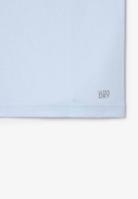 Section de tissu bleu clair avec un ourlet cousu et un petit texte "ULTRA DRY" imprimé près du bord inférieur sur le côté droit.