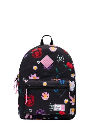 Sac à dos noir avec imprimé floral coloré, poche avant zippée, tirettes de fermeture éclair roses et petite pièce carrée rose texturée près du centre supérieur.