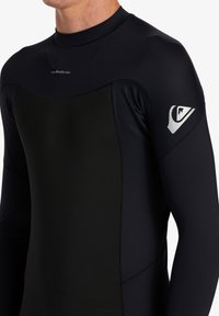 Čierny rash guard vyrobený z elastického materiálu s dlhými rukávmi. Obsahuje matný povrch a logo na pravej ramene.