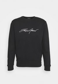 Svart sweatshirt i bomull med rund halsringning och långa ärmar. Har en vit signaturlogga över bröstet.