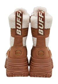 Botas marrones y crema de media caña con un upper texturizado y esponjoso, suela de goma y gran branding "BUFFALO" en la parte trasera. Detalles redondos del logo.