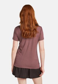 Kortärmad, mörkröd T-shirt med mjuk textur, rund halsringning och en något figurnära passform. Kombinerad med en flödande svart kjol.